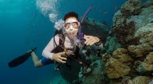 Relaxed scuba diver exploring a coral reef in Koh Tao during a fun dive with Echo Divers Koh Tao
