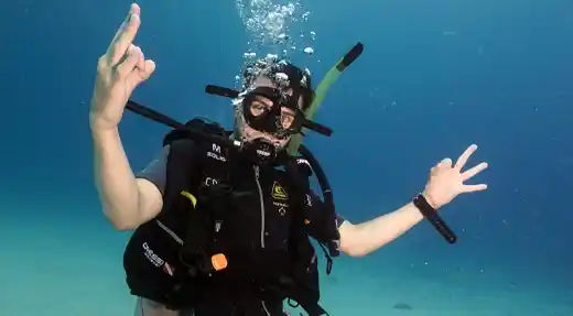 Diver practicing underwater skills during the SSI Stress & Rescue course with Echo Divers Koh Tao, giving fun hand signals.