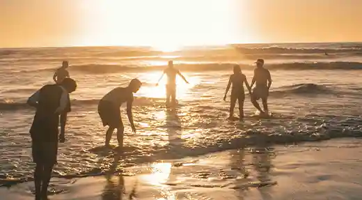 Group of friends playing in the shallow water during a golden sunset on Koh Tao Thailand.