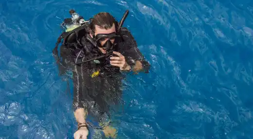 Scuba diver in full gear floating in calm water during training