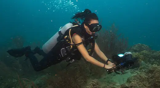 Echo Divers Koh Tao pro underwater photography course diver shooting the reef with a camera housing and video light, Koh Tao, Thailand