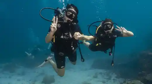 Two Echo Divers Koh Tao students underwater above coral reef during a Basic Diver dive in Koh Tao, Thailand